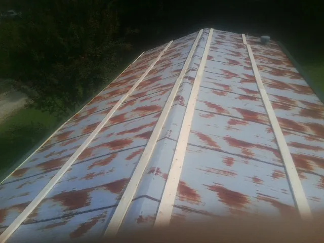 Rusted metal roof panels with new wood purlins before replacement — Storm Damage Roof Repair in Harrisonville by Roofing Brothers