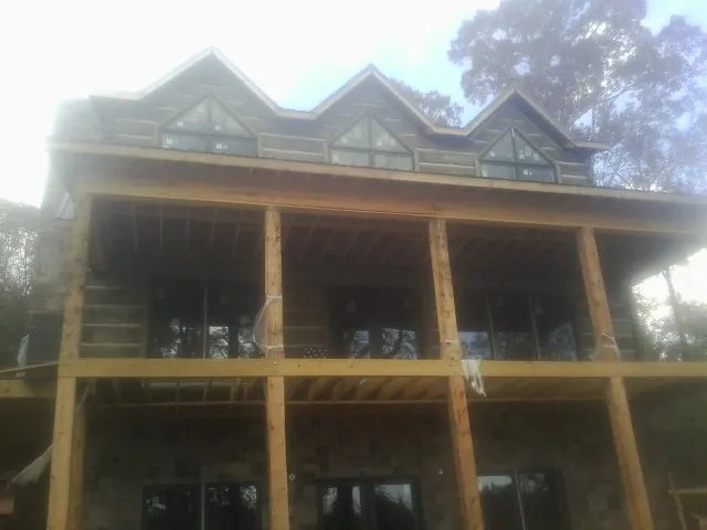 Dormers and porch framing on a large log home under construction — Roof Coating work by our crew in Harrisonville