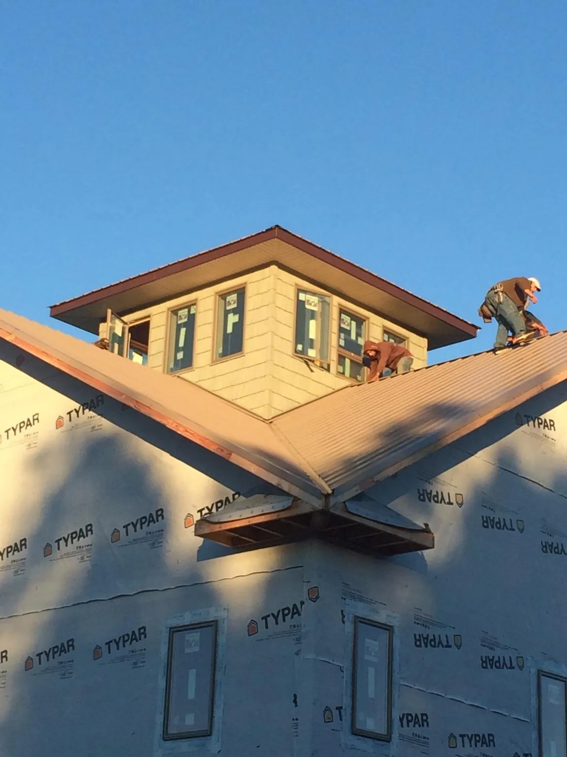 Roofers working around a rooftop cupola on a new metal roof at sunset — Roof Waterproofing in Harrisonville by Roofing Brothers